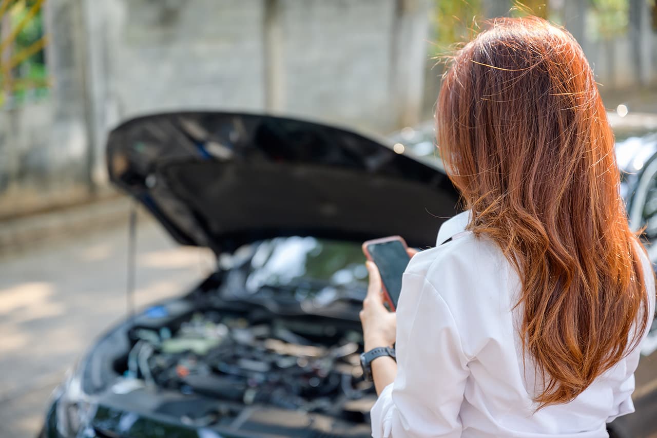 故障した車と女性の後ろ姿